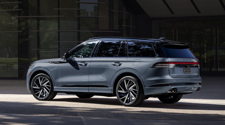 A Whisper Blue 2025 Lincoln Black Label Aviator® SUV is parked outside a modern building. | Friendly Lincoln in Monroe MI