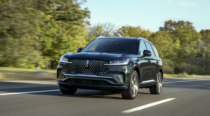 A 2025 Lincoln Black Label Aviator® SUV is being driven down a road lined with trees. | Friendly Lincoln in Monroe MI