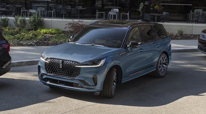 A Whisper Blue 2025 Lincoln Aviator® SUV is parked outside a modern building showcasing the driver’s side of the vehicle. | Friendly Lincoln in Monroe MI