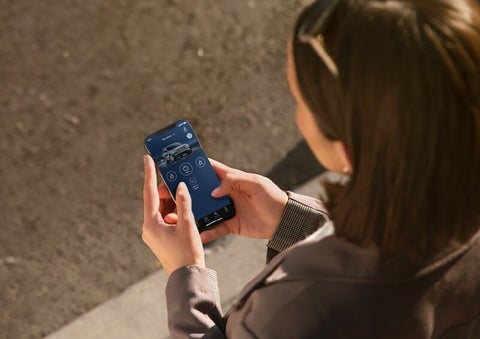 A person is shown interacting with a smartphone to connect to a Lincoln vehicle via the Lincoln Way® App. | Friendly Lincoln in Monroe MI