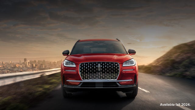 A 2025 red Lincoln Corsair® SUV is being driven down a road at sunset. | Friendly Lincoln in Monroe MI