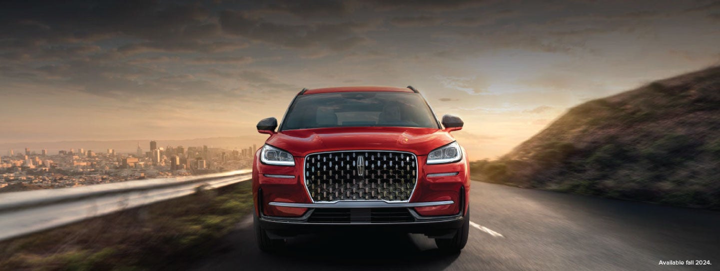 A 2025 red Lincoln Corsair® SUV is being driven down a road at sunset. | Friendly Lincoln in Monroe MI