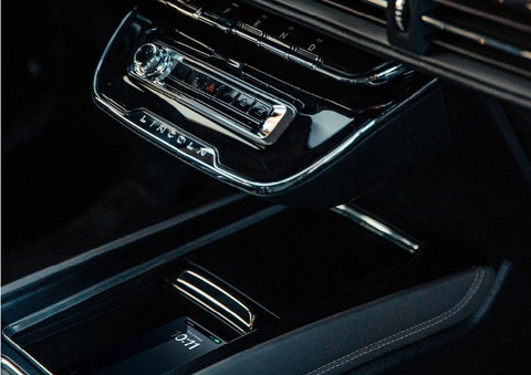 A smartphone is is being placed on the wireless charging pad in the front center console cubby. | Friendly Lincoln in Monroe MI