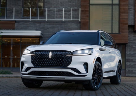 A 2026 Lincoln Aviator® Reserve model is shown with the available Jet Appearance Package parked near a restaurant. | Friendly Lincoln in Monroe MI