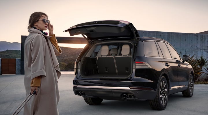 A woman approaches a 2026 Lincoln Aviator® SUV with its rear liftgate open. | Friendly Lincoln in Monroe MI