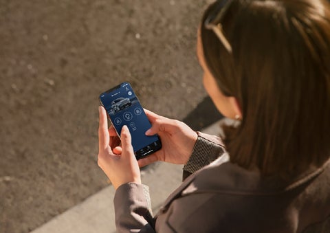 A person is shown interacting with a smartphone to connect to a Lincoln vehicle via the Lincoln Way® app. | Friendly Lincoln in Monroe MI