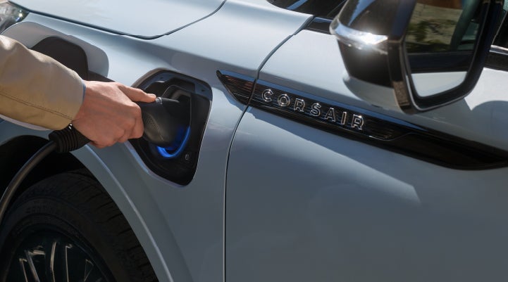 A hand is plugging in a 2026 Lincoln Corsair® Grand Touring Plug-in Hybrid SUV. | Friendly Lincoln in Monroe MI