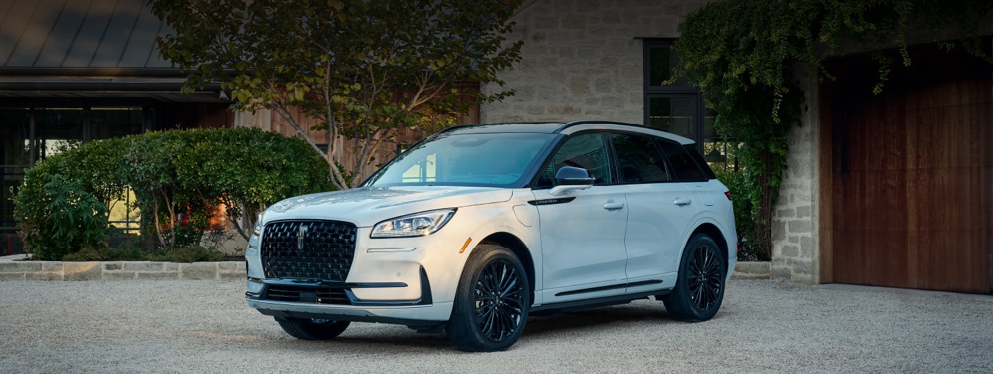 A 2026 Lincoln Corsair® SUV is parked in front off a luxury home. | Friendly Lincoln in Monroe MI