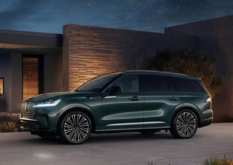 A green 2027 Lincoln Aviator® SUV is parked outside a contemporary home. | Friendly Lincoln in Monroe MI