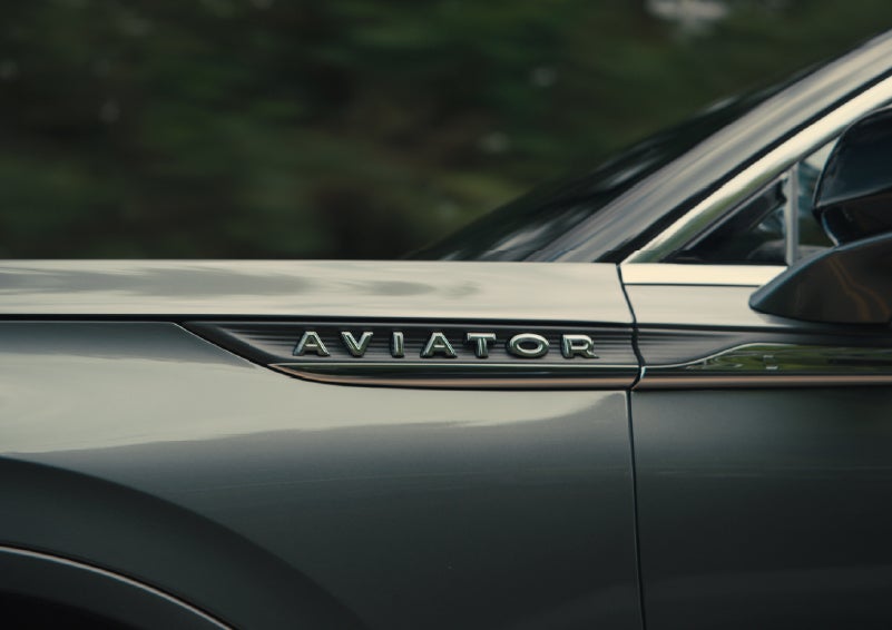 The driver’s side door and fender badging of a gray 2027 Lincoln Aviator® SUV are showcased. | Friendly Lincoln in Monroe MI
