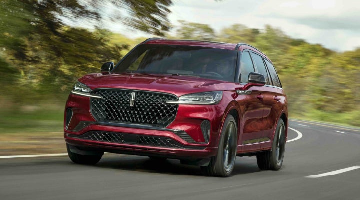 A 2027 Lincoln Aviator® SUV is being driven on a country road | Friendly Lincoln in Monroe MI