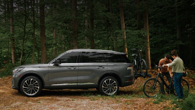 A father and son load e-bikes on a bike rack attached to a 2027 Lincoln Aviator® SUV. | Friendly Lincoln in Monroe MI